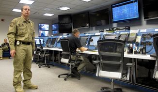 In this Nov. 3, 2015, photo, Max Raterman, left, who directs the U.S. Customs and Border Protection Air and Marine Operations at Grand Forks Air Force Base, N.D, monitors work in the operations center. Contract employee Jeff Deem, right, is following an unmanned flight that originated at the center. The CBP flies drones out of three U.S. cities. (AP Photo/Dave Kolpack)