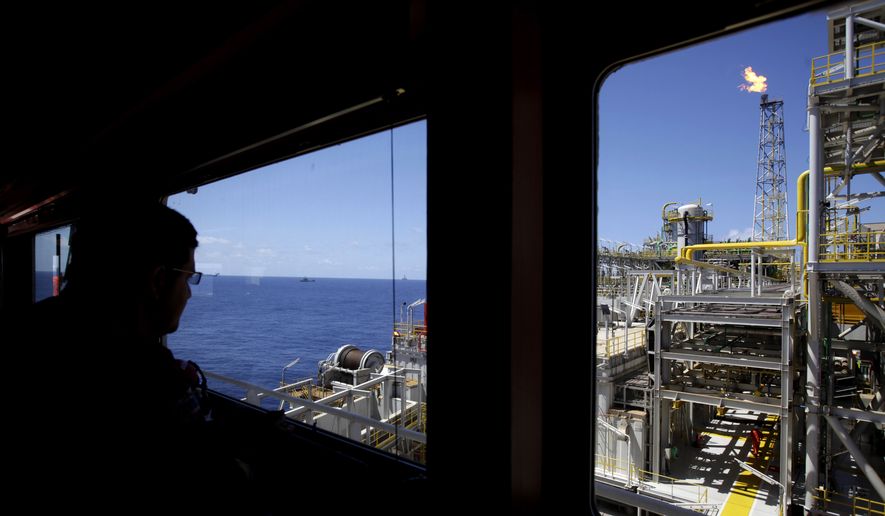 An oil worker looks out, over the Petrobras offshore ship platform over Tupi field in Santos Bay off the coast of Rio de Janeiro, Brazil, in this Oct. 28, 2010, file photo. Climate change could push more than 100 million people into extreme poverty by 2030 by disrupting agriculture and fueling the spread of malaria and other diseases, the World Bank said in a report Sunday Nov. 8, 2015, also stating that carbon emissions are expected to rise for many years as China, India and other developing countries expand the use of fossil fuels to power their economies. (AP Photo/Felipe Dana, FILE)