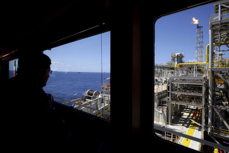 An oil worker looks out, over the Petrobras offshore ship platform over Tupi field in Santos Bay off the coast of Rio de Janeiro, Brazil, in this Oct. 28, 2010, file photo. Climate change could push more than 100 million people into extreme poverty by 2030 by disrupting agriculture and fueling the spread of malaria and other diseases, the World Bank said in a report Sunday Nov. 8, 2015, also stating that carbon emissions are expected to rise for many years as China, India and other developing countries expand the use of fossil fuels to power their economies. (AP Photo/Felipe Dana, FILE)