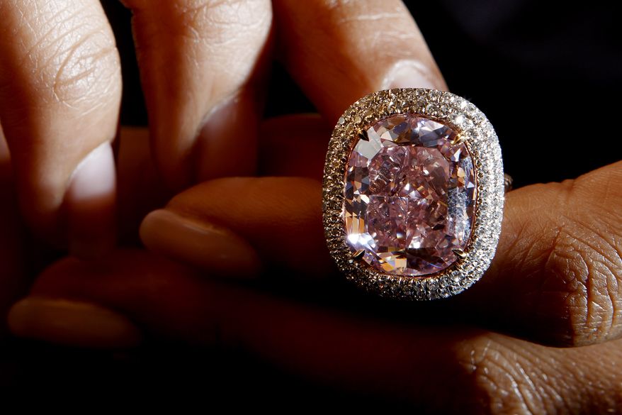 A Christie's employee presents a cushion-shaped fancy Vivid Pink diamond of 16.08 carats, during a preview at the Christie's auction house in Geneva, Switzerland, Friday, Oct. 30, 2015. The vivid diamond is estimated between $23 million to $28 million and will be sold during the Christie's auction Nov. 10 in Geneva. (Salvatore Di Nolfi/Keystone via AP, file)