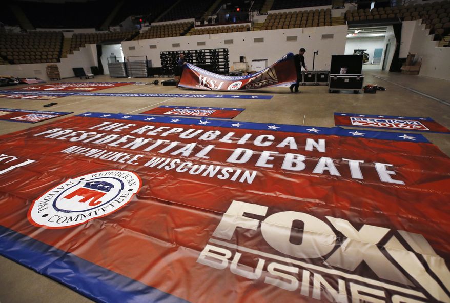 Workers put up banners in preparation for Tuesday's Republican debate, Monday, Nov. 9, 2015, in Milwaukee. (AP Photo/Morry Gash)