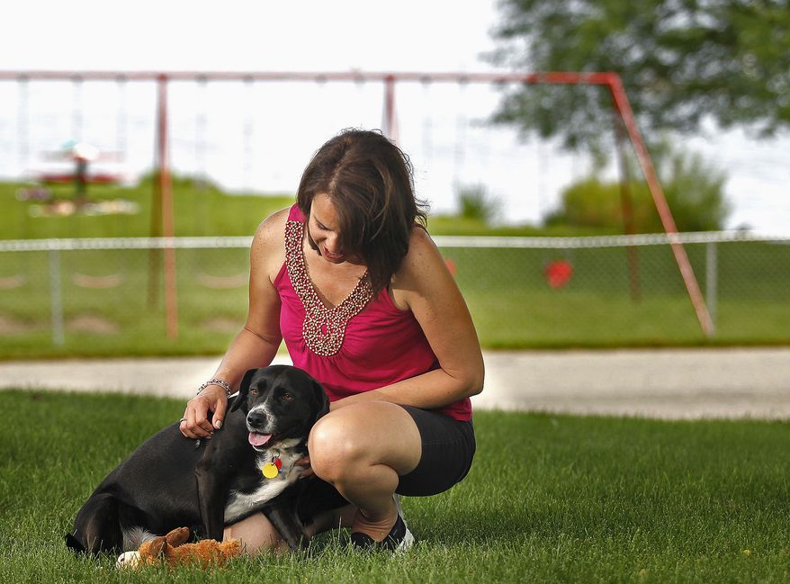 In this July 28, 2015, photo, Lisa Kruczek pets Bailey, one of her clients' dogs, in her yard in Wonder Lake, Ill. Kruczek operates her home-based business, Lakeside Pet Sitting & Grooming, with the help of Dogvacay.com, a website which finds local pet sitters for vacationing families. (Matthew Apgar/Northwest Herald via AP) MANDATORY CREDIT, CHICAGO TRIBUNE OUT