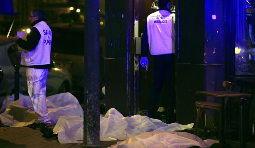 Victims lay on the pavement in a Paris restaurant, Friday, Nov. 13, 2015. Two police officials say at least 11 people have been killed in shootouts and other violence around Paris. Police have reported shootouts in at least two restaurants in Paris, and at least two explosions have been heard near the Stade de France stadium, and French media is reporting of a hostage-taking in the capital. (AP Photo/Thibault Camus)