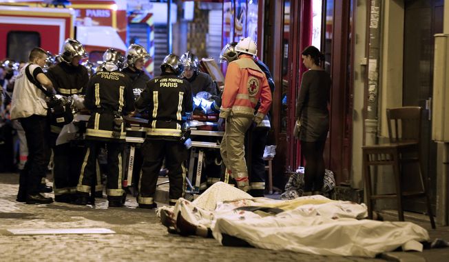 Rescue workers gather at victims in the 10th district of Paris, Friday, Nov. 13, 2015. Several dozen people were killed in a series of unprecedented attacks around Paris on Friday, French President Francois Hollande said, announcing that he was closing the country&#x27;s borders and declaring a state of emergency. (AP Photo/Jacques Brinon)