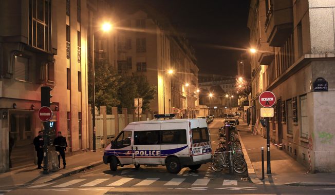 Police officers stand in a street next to Le Carillon, a bar-cafe where people were killed and several gravely injured, according to the prosecutor, in Paris, Saturday, Nov. 14, 2015. A series of attacks targeting young concert-goers, soccer fans and Parisians enjoying a Friday night out at popular nightspots killed over 100 people in the deadliest violence to strike France since World War II. (AP Photo/Thibault Camus)