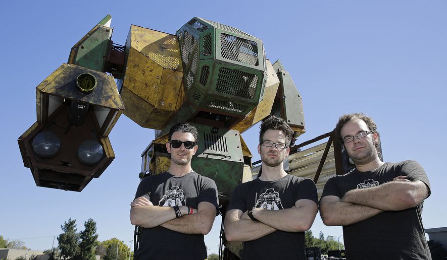 MegaBots founders from left, Brinkley Warren, Matt Oehrlein and Gui Cavalcanti stand below their 15-foot tall, piloted Mk.II robot at the Pioneer Summit in Redwood City, Calif., in this Oct. 9, 2015, file photo. (AP Photo/Eric Risberg)