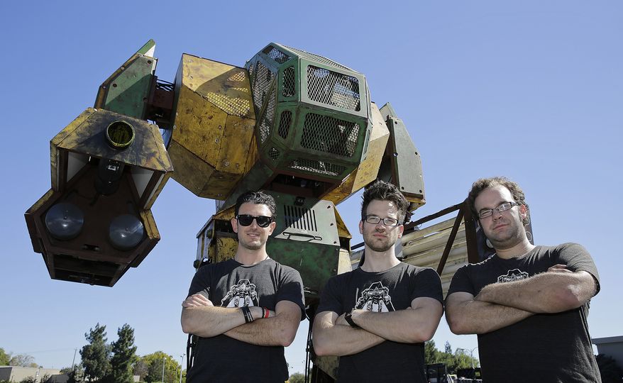 MegaBots founders from left, Brinkley Warren, Matt Oehrlein and Gui Cavalcanti stand below their 15-foot tall, piloted Mk.II robot at the Pioneer Summit in Redwood City, Calif., in this Oct. 9, 2015, file photo. (AP Photo/Eric Risberg)
