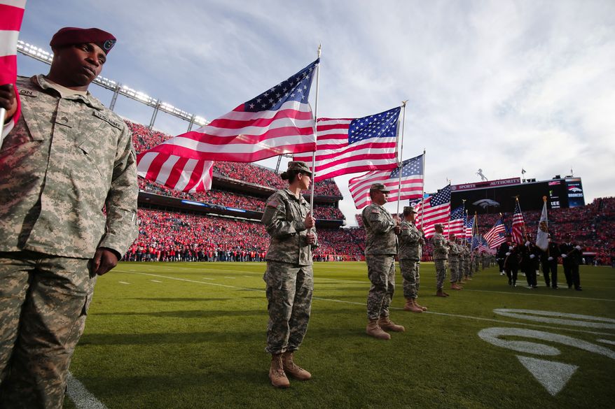 Servicemen hold American flags on the field during an NFL football game between the Denver Broncos and the Kansas City Chiefs. (AP Photo/Jack Dempsey)