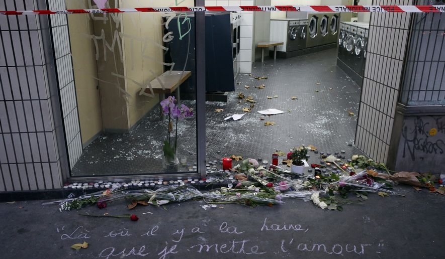 A graffiti on the pavement reads "Where there is hate, I want to bring love" next to candles and flowers at rue de La Fontaine au Roi in Paris, France, on Monday, Nov. 16, 2015. (Associated Press)