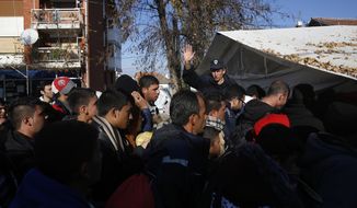 Serbian police officer attempt to organize migrants queuing to get registered at a refugee center in the southern Serbian town of Presevo, Monday, Nov. 16, 2015. Refugees fleeing war by the tens of thousands fear the Paris attacks could prompt Europe to close its doors, especially after police said a Syrian passport found next to one attacker&#39;s body suggested its owner passed through Greece into the European Union and on through Macedonia and Serbia last month. (AP Photo/Darko Vojinovic)