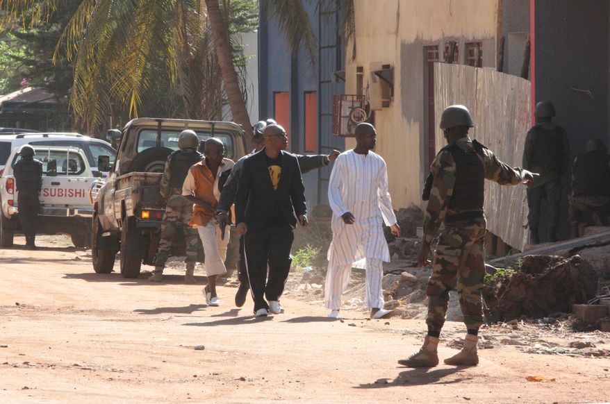 Security force personnel escort people fleeing from the Radisson Blu Hotel in Bamako, Mali, Friday, Nov. 20, 2015. The company that runs the Radisson Blu Hotel in Mali's capital says assailants have takenhostages in a brazen assault involving grenades. (AP Photo/Harouna Traore)