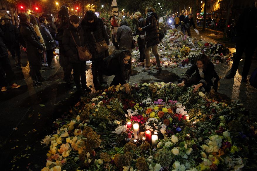 People set flowers outside the Bataclan concert hall after French artists and cultural figures are calling for people to mark a week since the start of the Paris attacks with an outpouring of "noise and light., Friday Nov.20, 2015. French President Francois Hollande will preside over a national ceremony Nov. 27 honoring the at least 130 victims of the deadliest attacks on France in decades.