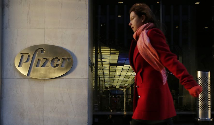 A woman passes Pfizer's world headquarters, Monday, Nov. 23, 2015, in New York. Pfizer and Allergan will join in a $160 billion deal to create the world's largest drugmaker. (AP Photo/Mark Lennihan)