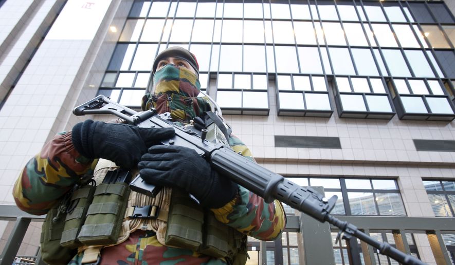 A Belgian police officer guards the building of the European Commission in Brussels, Belgium, Tuesday, Nov. 24, 2015. Brussels is keeping its terror alert at the highest level. (AP Photo/Michael Probst)