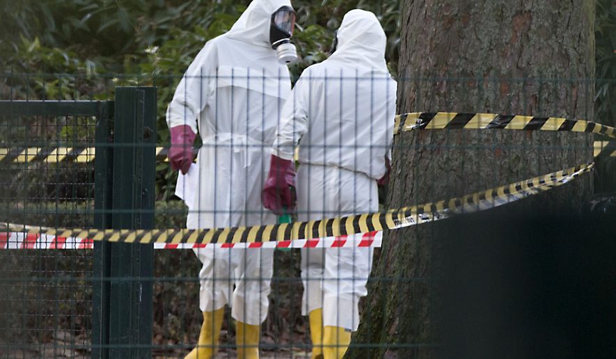 Two men in white hazmat suits stand at the entrance of the Grand Mosque of Brussels on Thursday, Nov 26, 2015. Emergency personnel responded at the mosque after a suspicious package was found. (AP Photo/Virginia Mayo)