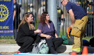 Two women speak with a firefighter at the triage area near the scene of a shooting in San Bernardino, Calif. on Wednesday, Dec. 2, 2015. Police responded to reports of an active shooter at a social services facility.   (Micah Escamilla/Los Angeles News Group via AP)