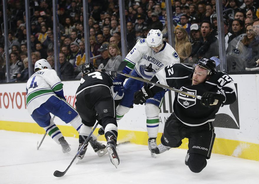 Los Angeles Kings' Trevor Lewis, right, takes a tumble after colliding with Vancouver Canucks' Luca Sbisa, center right, of Italy, as Canucks' Matt Bartkowski, left, and Kings' Kyle Clifford fight for the puck during the second period of an NHL hockey game, Tuesday, Dec. 1, 2015, in Los Angeles. (AP Photo/Jae C. Hong)