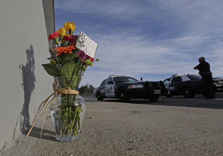 Flowers are left by the side of the road as a San Bernardino police officer blocks the road leading to the site of yesterday&#x27;s mass shooting on Thursday, Dec. 3, 2015 in San Bernardino, Calif.  A heavily armed man and woman dressed for battle opened fire on a holiday banquet for his co-workers Wednesday, killing multiple people and seriously wounding others in a precision assault, authorities said. Hours later, they died in a shootout with police. (AP Photo/Chris Carlson)