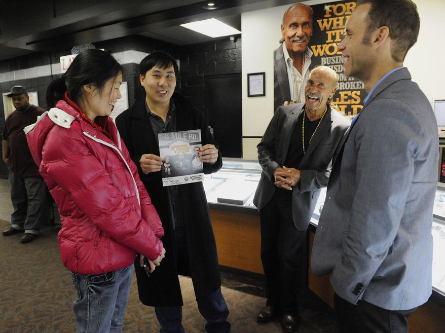 ADVANCE FOR THE WEEKEND OF DEC. 5-6 - In this Thursday, Nov. 19, 2015 photo, Micah Chiang, second left, with his wife Hannah Chiang of Perth, Australia, shows off an autographed photo he received from Les Gold, second right, as his son Seth watches at American Jewelry & Loan, founded by Les Gold, in Detroit. The pawn shop featured in a reality TV show has drawn tourists. (David Coates/Detroit News via AP) MANDATORY CREDIT