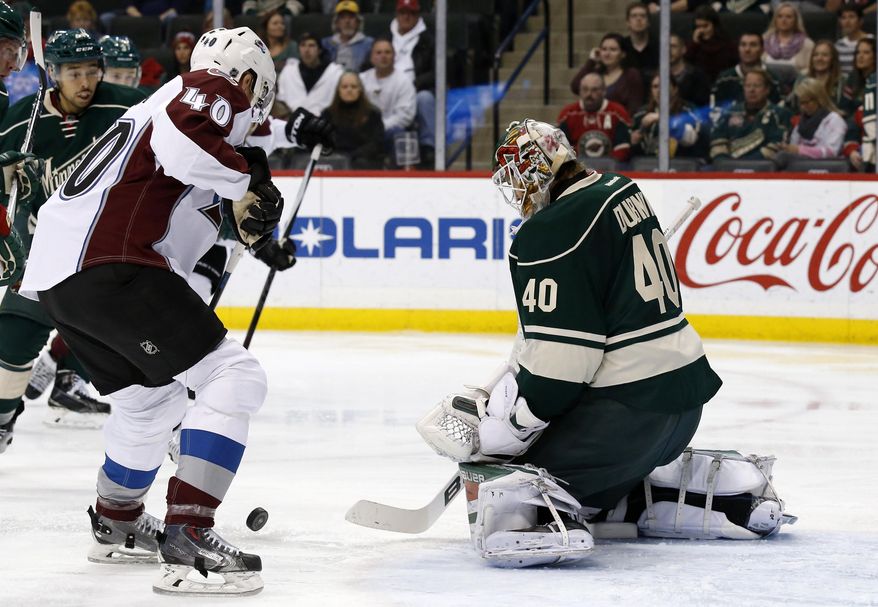 Minnesota Wild goalie Devan Dubnyk, right, deflects a shot in front of Colorado Avalanche left wing Alex Tanguay, left, during the second period of an NHL hockey game in St. Paul, Minn., Saturday, Dec. 5, 2015. (AP Photo/Ann Heisenfelt)
