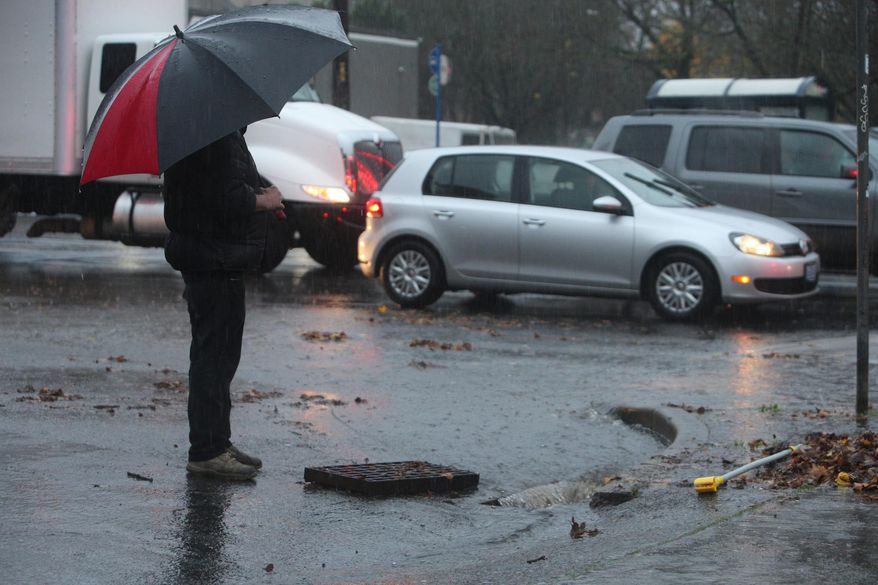 Pouring rain and clogged storm drains caused flooding in the streets near the corner of SE 12th and Hawthorne in Portland Ore., Monday, Dec. 7, 2015. The National Weather Service on Monday issued a flood watch for much of northwest Oregon and southwest Washington. (Dave Killen/The Oregonian via AP)