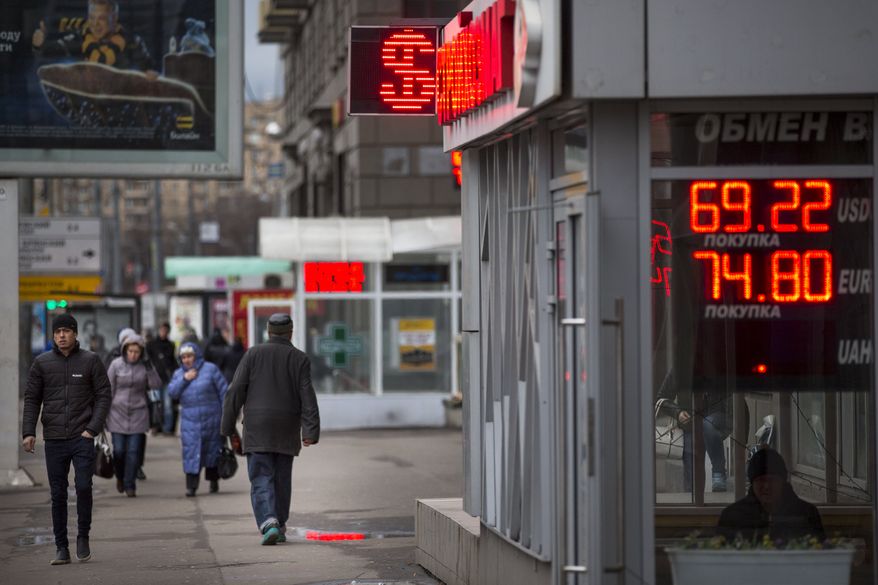 People walk past an exchange office sign showing the currency exchange rates of Russian ruble, U.S. dollar, and euro in Moscow, Russia, Tuesday, Dec. 8, 2015. The ruble continued to decline on Tuesday as oil prices are reaching a seven-year low. (AP Photo/Alexander Zemlianichenko)