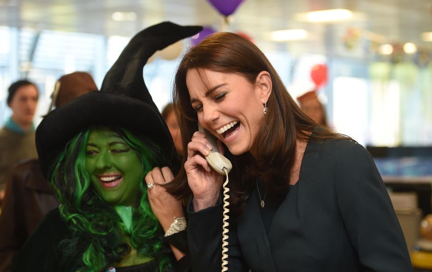Kate Duchess of Cambridge laughs on the phone as a trader in fancy dress looks on as the Duches attends ICAP's 23rd annual Charity Day in London Wednesday Dec. 9, 2015. The Duchess and Prince William joined ICAP' s brokers to raise revenues from trading on ICAP's charity day that will be donated to a range of charities, including SkillForce, of which William is patron, and SportsAid and Place2Be, of which Kate is patron. (Jeremy Selwyn, Pool via AP)