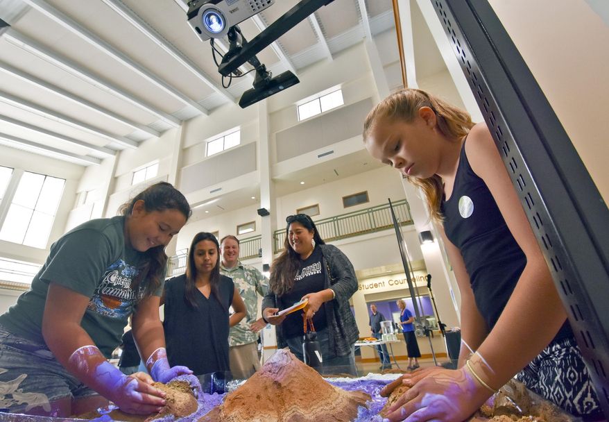 ADVANCE FOR WEEKEND DEC. 12-13, 2015 AND THEREAFTER - In this Nov. 30, 2015 photo, Makani Brun and Anela Wilczewski build up mountains using sand from Kalapaki Beach under the rays of a depth and height sensor, during an open house of the Geographic Information Systems course at Kauai Community College in Puhi, Hawaii. The open house at the college was intended to provide information about the professional opportunities available to those who receive training to become GIS analysts. According to the U.S. Bureau of Labor Statistics, employment of surveyors, cartographers, photogrammetrists, and surveying and mapping technicians is expected to grow through 2018. (Dennis Fujimoto/The Garden Island via AP)