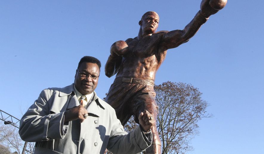 In this photo taken Monday, Dec. 7, 2015, Hall of Fame boxer Larry Holmes poses by a statue of his likeness as construction crews complete the installation of the new statue at Scott Park, where the Lehigh river runs into the Delaware in Easton, Pa. A dedication of the statue will take place Sunday, Dec. 13. (Sue Beyer/The Express-Times via AP)