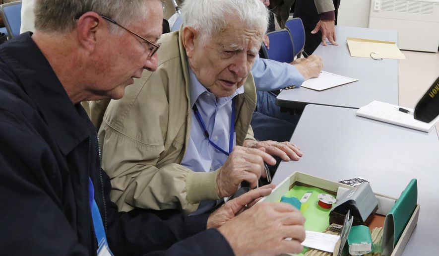 Scott Downing, 96, of Amarillo, TX, center, accompanied by his son, Stuart, looks at a model of the area where his plane crashed at a community hall during his retrospective visit to Inzai, a town 40 kilometers (25 miles) northeast of Tokyo, where he was taken prisoner of war 70 years ago, Friday, Dec. 11, 2015. Three of the 11-member crew were killed that night of May 25, 1945, when their B-29 was shot down, crashing into bamboo groves as they were flying back from a bombing raid on Tokyo. In an emotional moment, Downing was given a hero’s welcome by Inzai, which had given the U.S. airmen proper burials at a temple and mourned their deaths, defying the stereotypes about wartime animosity. (AP Photo/Yuri Kageyama)