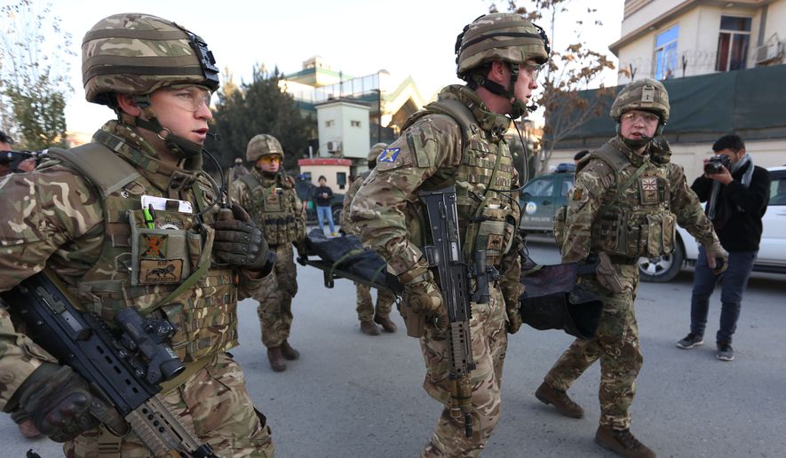 British soldiers carry the body of a victim of an attack that happened near the Spanish embassy, in Kabul, Afghanistan, Saturday, Dec. 12, 2015. Explosions and gunfire rocked a diplomatic area of central Kabul overnight as security forces tried to flush out Taliban attackers who claimed responsibility for a deadly car bomb Friday. (AP Photo/Rahmat Gul)