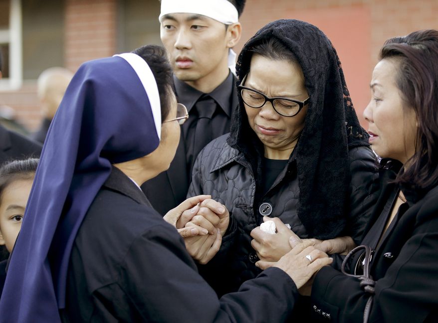 Van Thanh Nguyen, center, is greeted by a nun as she arrives for her daughter Tin Nguyen's funeral on Saturday, Dec. 12, 2015, in Santa Ana, Calif. Nguyen died in the mass shootings in San Bernardino, Calif., on Dec. 2. (AP Photo/Chris Carlson)