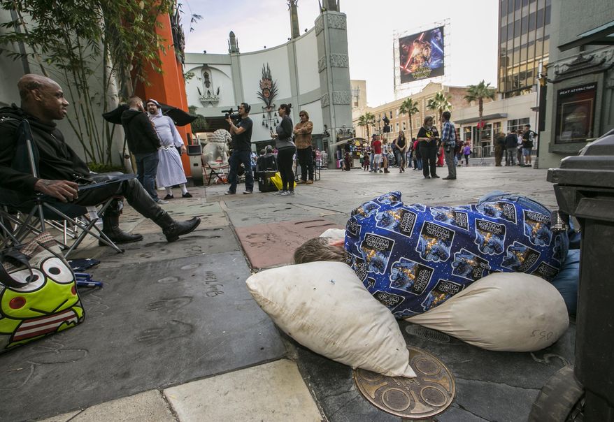 "Star Wars" fans Deuce Wayne, from Virginia, left, and Larry Ross from La Crescenta, Calif., right, rest while waiting in line up outside the TCL Chinese Theater Imax for the "Star Wars: The Force Awakens" premiere in Los Angeles, in this Dec. 9, 2015, file photo. Fans waited in line outside of the historic theater as part of a charity event to raise money for the Starlight Children's Foundation. (AP Photo/Damian Dovarganes, File)