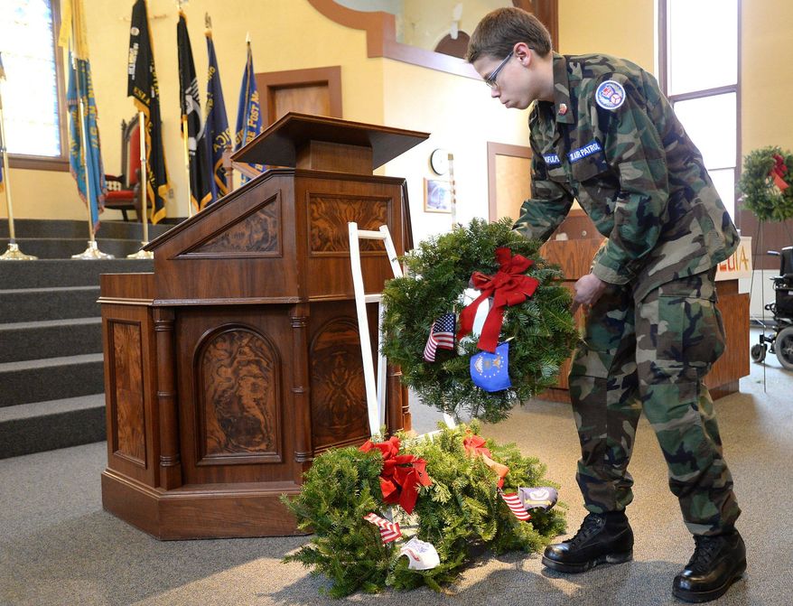 William Ghofulpo, 16, of the Erie Composite Squadron 502 of the Civil Air Patrol, U.S. Air Force, carries a wreath during the Wreathes Across America ceremony Dec. 12 at the Pennsylvania Soldiers' & Sailors' Home in Erie, Pa. (Jack Hanrahan/Erie Times-News via AP) MANDATORY CREDIT; MAGS OUT