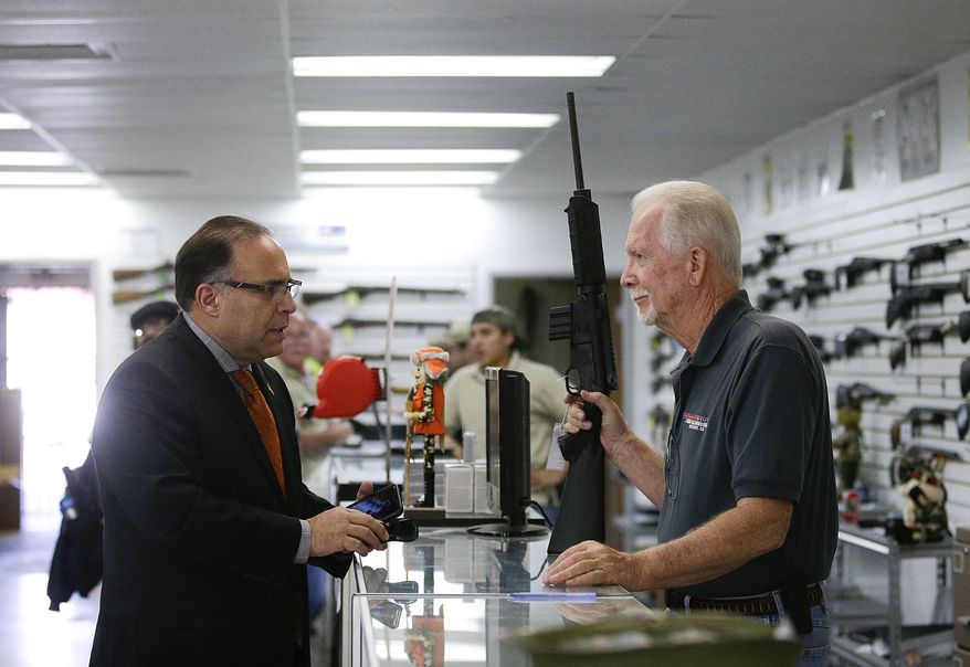 Sales associate Mike Conway (right) shows Paul Angulo a semiautomatic rifle at Bullseye Sport gun shop in Riverside, Calif., on Dec. 9, 2015. (Associated Press) **FILE**