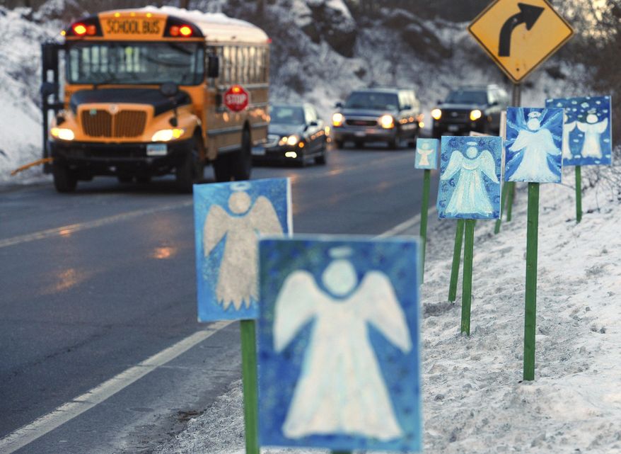 FILE - In this Jan. 3, 2013, file photo, a bus traveling from Newtown, Conn., to Monroe stops near 26 angel signs posted along the roadside in Monroe, Conn., on the first day of classes for Sandy Hook Elementary School students since the Dec. 14, 2012, shooting. The massacre in Newtown, in which a mentally troubled young man killed 26 children and teachers, served as a rallying cry for gun-control advocates across the nation. But in the three years since, many states have moved in the opposite direction, embracing the National Rifle Association’s axiom that more “good guys with guns” are needed to deter mass shootings. (AP Photo/Jessica Hill, File)