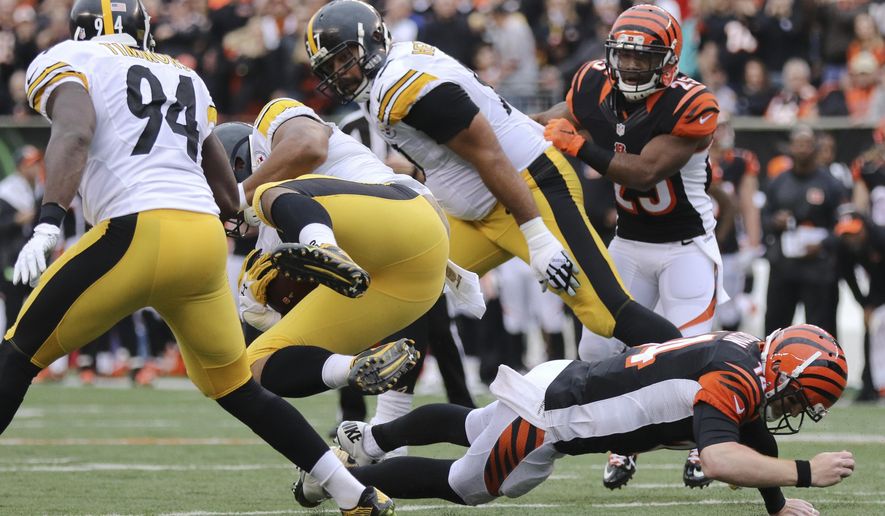 Cincinnati Bengals quarterback Andy Dalton, right, tackles Pittsburgh Steelers defensive end Stephon Tuitt, center left, after Tuitt caught an interception in the first half of an NFL football game, Sunday, Dec. 13, 2015, in Cincinnati. (AP Photo/Gary Landers)