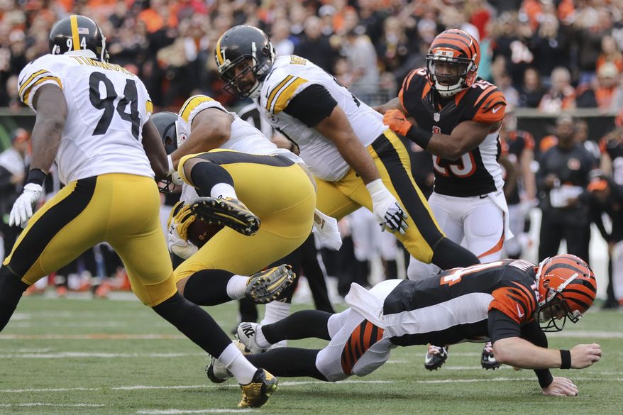 Cincinnati Bengals quarterback Andy Dalton, right, tackles Pittsburgh Steelers defensive end Stephon Tuitt, center left, after Tuitt caught an interception in the first half of an NFL football game, Sunday, Dec. 13, 2015, in Cincinnati. (AP Photo/Gary Landers)