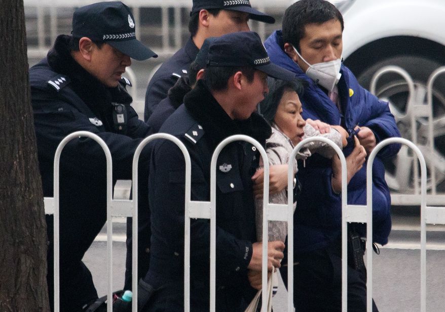 Police officers take away a supporter of rights lawyer Pu Zhiqiang near the Beijing Second Intermediate People's Court during his trial in Beijing, Monday, Dec. 14, 2015. Pu went on trial Monday on charges of provoking trouble with commentaries on social media that were critical of the ruling Communist Party. (AP Photo/Andy Wong)
