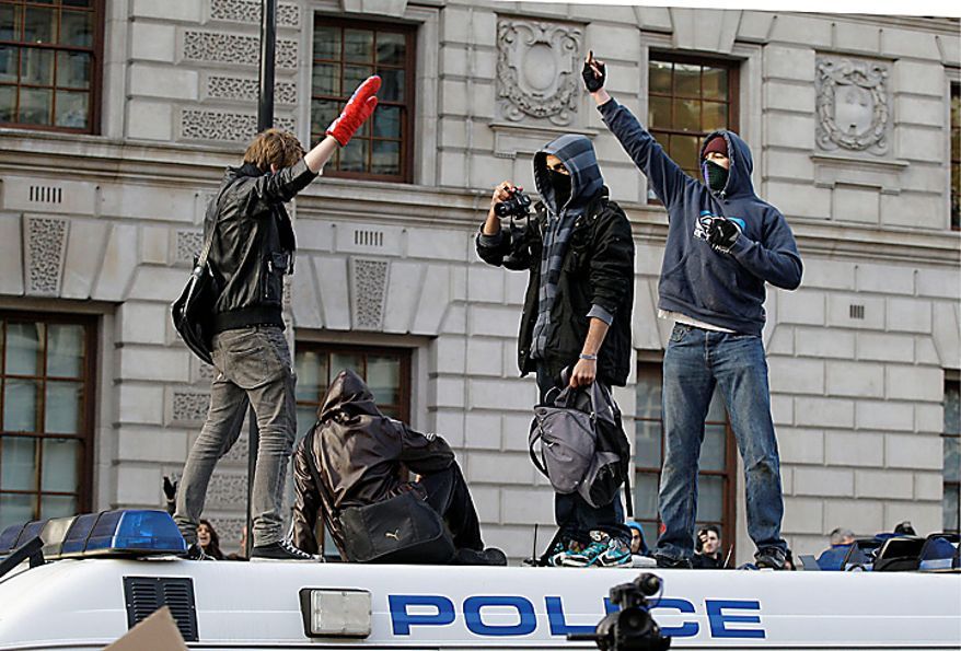 Protesters gesture on top of a stranded police van as thousands of students protest against increased tuition fees at Whitehall in London, Wednesday, Nov. 24, 2010. (AP Photo/Sang Tan)