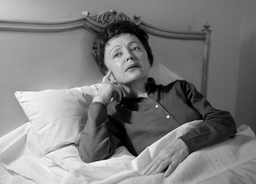 FILE - In this Feb. 20, 1959 file photo, French songstress Edith Piaf props up in bed after an undisclosed illness resulted in the cancellation of scheduled performances at the Waldorf-Astoria Hotel in New York. Piaf, famous for her hit "La Vie En Rose," would have turned 100 on Dec. 19, 2015. At only 4 feet 8 inches, her voice was strong and distinctive, a trembling alto wail that became the voice of the Paris working class. Piaf died on Oct. 10, 1963, from exhaustion and liver disease at the age of 47. (AP Photo/Matty Zimmerman, File)