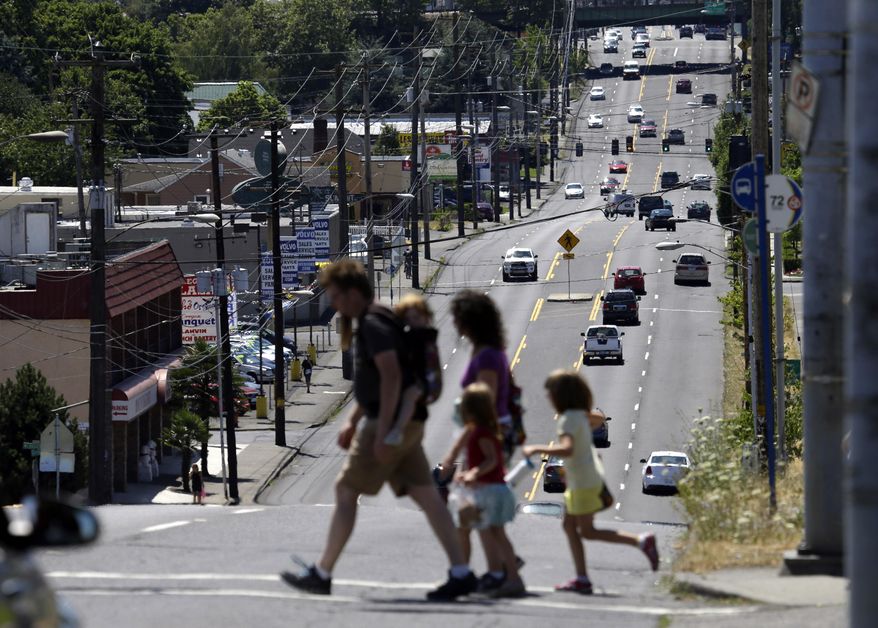 FILE - In this Tuesday, July 14, 2015, file photo, pedestrians cross the wide swath of 82nd Avenue in East Portland, Ore. The Avenue is traditionally considered the dividing line between Portland and East Portland, where shabby apartment complexes, fading strip malls, wide avenues and fast-food chains are the norm. Community leaders say Portland must do more to stop the displacement of residents caused by gentrification. Low-income and immigrant families say they're being pushed out of East Portland, a historically neglected part of town. Portland's tight rental market, coupled with new public and private investments in East Portland, are making the area more desirable to middle class residents. (AP Photo/Don Ryan, File)