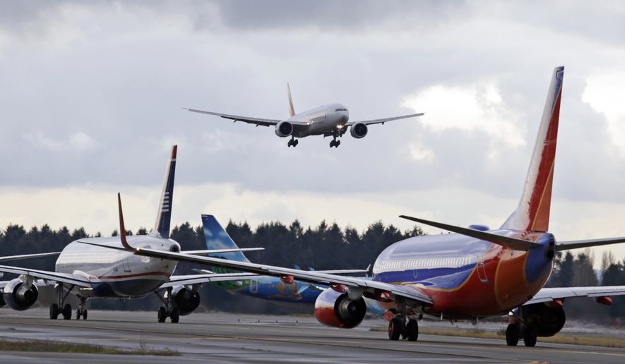 One passenger jet comes in for a landing and in view of a line of planes waiting to takeoff, Wednesday, Dec. 16, 2015, at Seattle-Tacoma International Airport, in SeaTac, Wash. (AP Photo/Elaine Thompson) ** FILE **