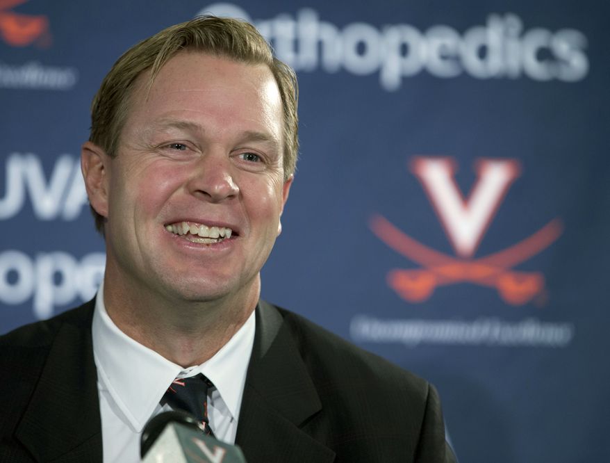 FILE - In this Monday, Dec. 7, 2015 file photo, New University of Virginia NCAA college head football coach, Bronco Mendenhall, smiles during a news conference at the school in Charlottesville, Va. Mendenhall takes over after his current team Brigham Young University competes in it's bowl game. Bronco Mendenhall and Kirby Smart are pulling double-duty this month after accepting head coaching positions with other programs. (AP Photo/Steve Helber)
