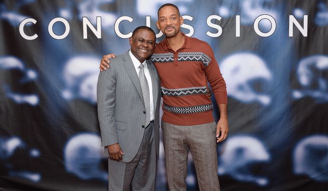 FILE - In this Dec. 14, 2015, file photo, Dr. Bennet Omalu, left, and actor Will Smith pose together at the cast photo call for the film &amp;quot;Concussion&amp;quot; at The Crosby Street Hotel in New York. In the trailer for the movie “Concussion,” Will Smith, portraying Omalu, says: “I found a disease that no one has ever seen.” It’s a claim that Omalu, a forensic pathologist, has himself made for years, often even giving a detailed description about how he came to name that disease “chronic traumatic encephalopathy.”  But Omalu neither discovered the disease nor named it, according to medical journals and concussion researchers who were interviewed by The Associated Press.  (Photo by Evan Agostini/Invision/AP, File)
