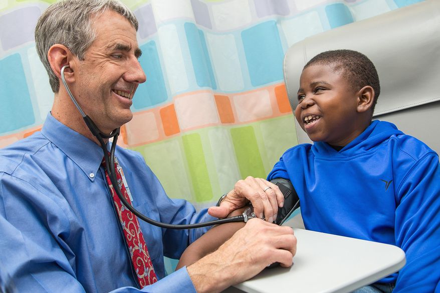 In this photo provided by the University of Virginia Health System, taken Dec. 9, 2015, Marshall Jones, right, laughs with Dr. John Barcia in the Battle Building at the University of Virginia Children's Hospital in Charlottesville, Va. A shake-up of the nation's kidney transplant system is getting more organs to patients once thought nearly impossible to match, according to early tracking of the new rules. (Coe Sweet/UVA Health System via AP) MANDATORY CREDIT