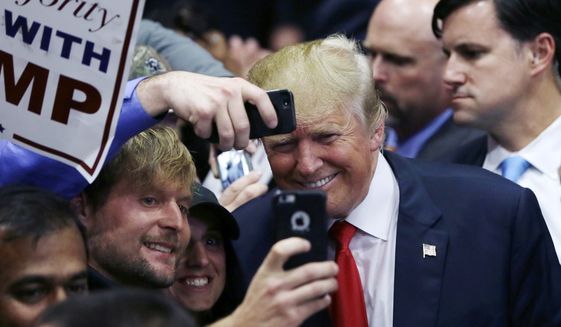 Republican presidential candidate Donald Trump poses with supporters after a campaign rally, Monday, Dec. 21, 2015, in Grand Rapids, Mich. (AP Photo/Carlos Osorio)