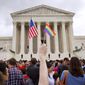 A man holds a U.S. and a rainbow flag outside the Supreme Court in Washington on June 16, 2015, after the court legalized gay marriage nationwide. (Associated Press) ** FILE **