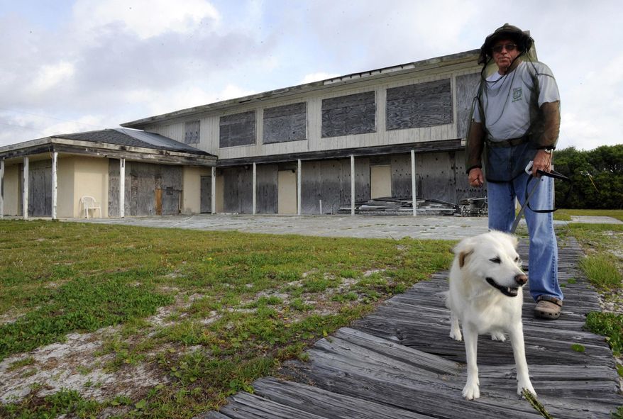 FILE - In this Friday, May 15, 2015 file photo, Ralph Gilges walks his dog Dixie outside Alabama's abandoned beachfront governor's mansion in Gulf Shores, Ala. Work began earlier this month to fix the 7,500-square-foot gubernatorial mansion that wasn’t repaired after Hurricane Danny in 1997. A spokeswoman for Gov. Robert Bentley says BP grant money left over from the 2010 oil spill will cover the $1.8 million in renovations. (AP Photo/Jay Reeves, File)