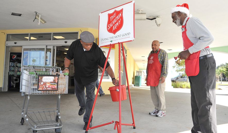 In this Dec. 9, 2015 photo, Walter Williams places his donation in a kettle next to Harold Pierce at a Publix store in Jacksonville, Fla. Pierce is among the top fundraisers for the regional Salvation Army Red Kettle Christmas campaign. At right is bell ringer Wilfred Jones. (Bruce Lipsky/The Florida Times-Union via AP)